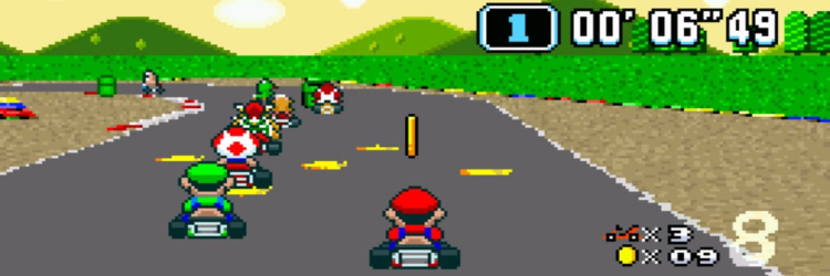 Fotograma del videojuego Super Mario Kart de la SNES. El jugador controla a Mario y va en último lugar. Parece que la carrera acaba de empezar porque se ve a los 8 corredores en la pantalla. Lo que se ve del circuito es una carretera rodeada de arena que gira hacia la izquierda, un fondo verde con montañas y un cielo soleado.